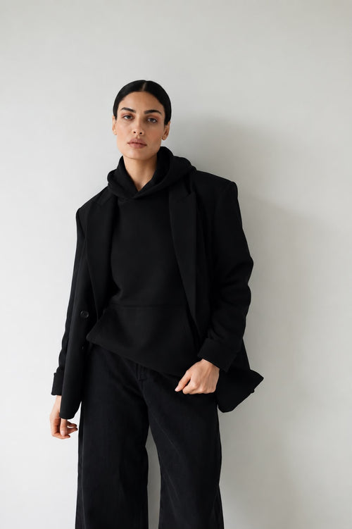 Woman wearing the black Le Butin8 Believe hoodie with a black blazer