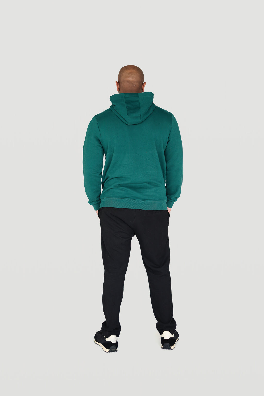 Back view of a man wearing the green Le Butin8 Gratitude hoodie