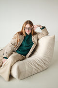 Woman seated wearing the green Le Butin8 Gratitude hoodie with a beige coat