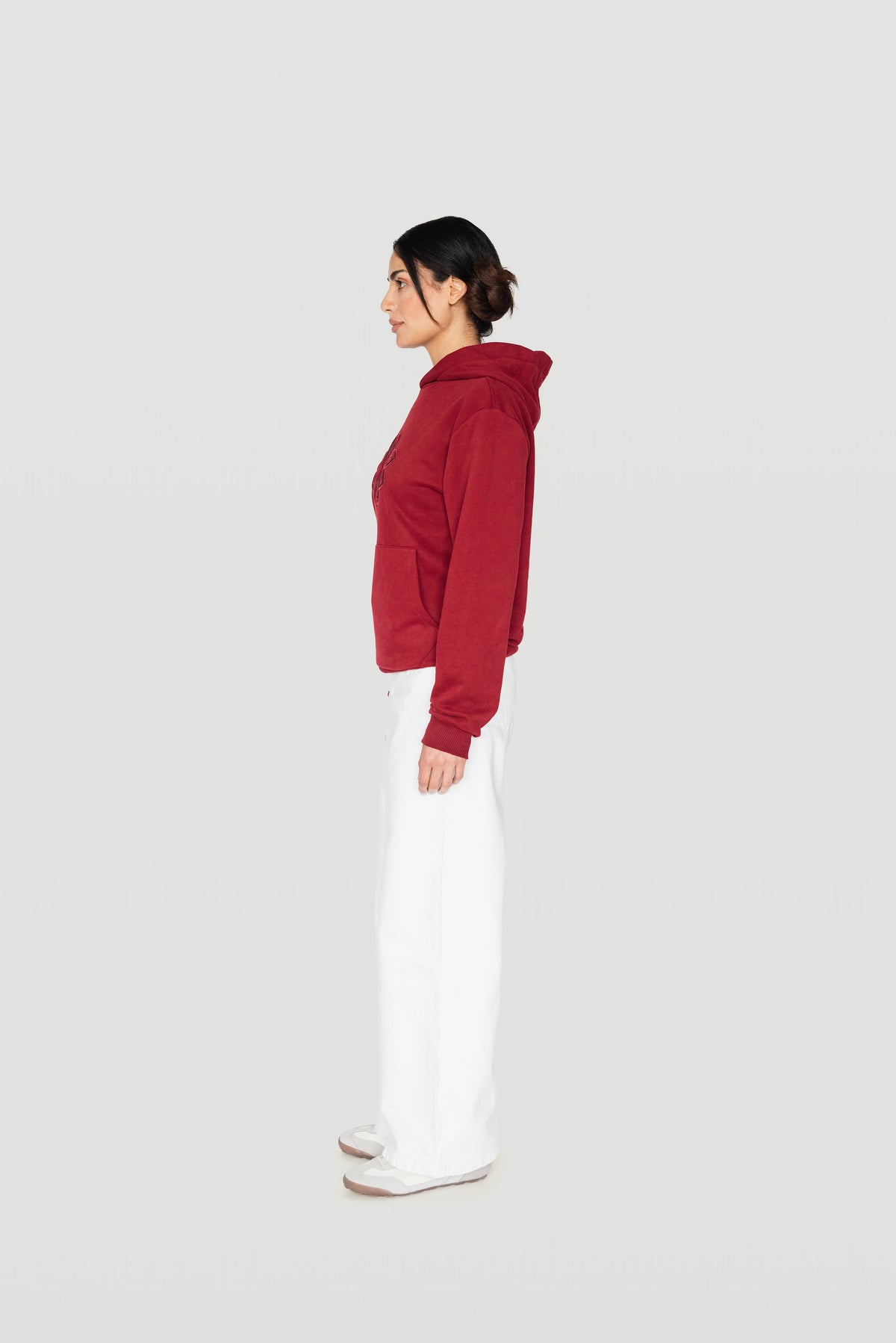 Side view of the bordeaux Le Butin8 Strength hoodie worn with white trousers