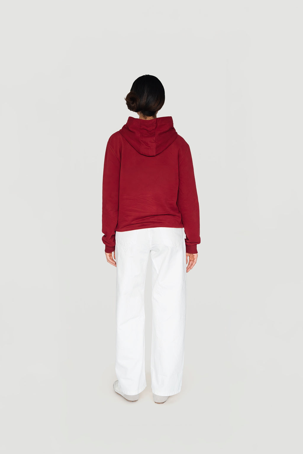 Back view of the bordeaux Le Butin8 Strength hoodie worn with white trousers