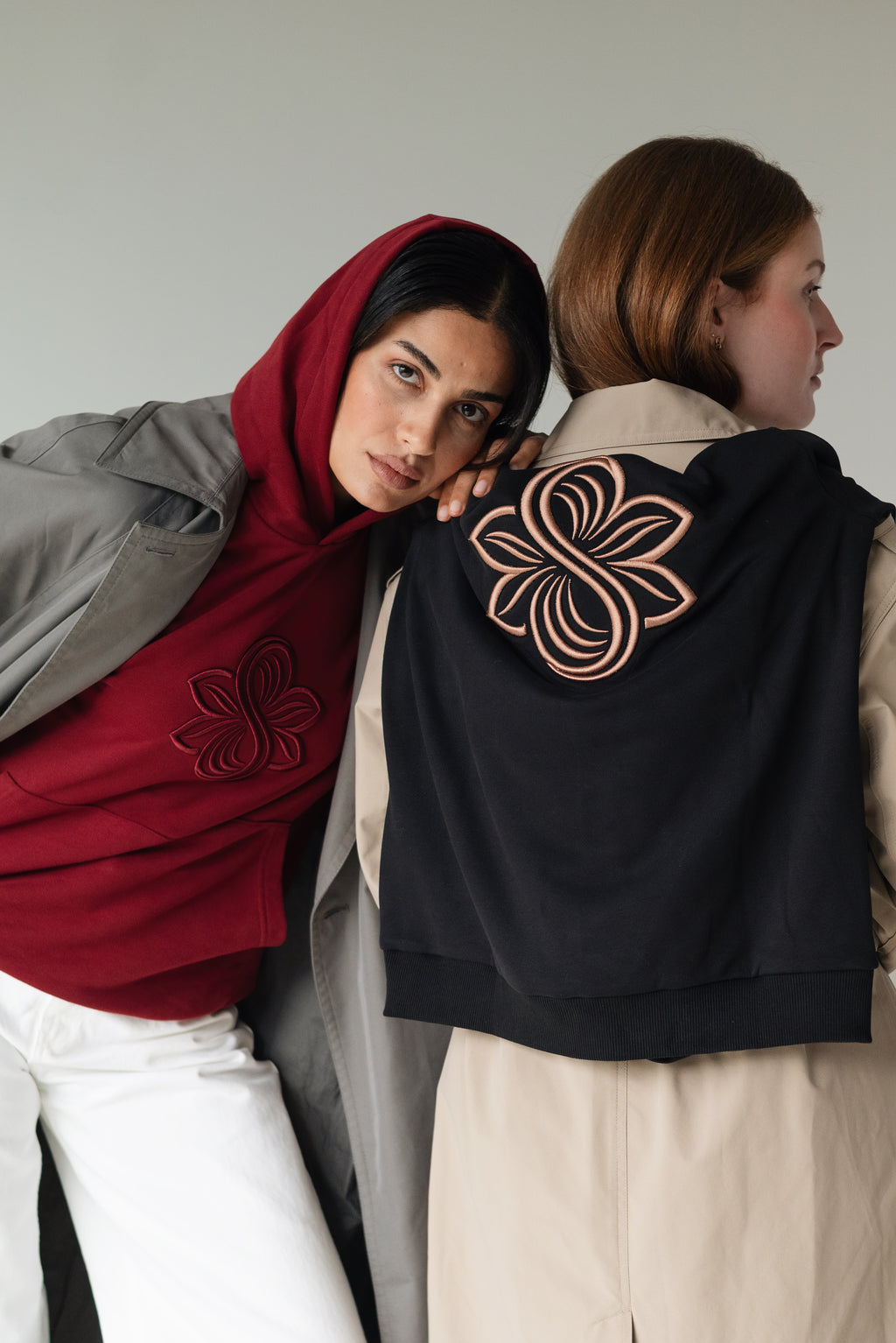 Two models seen from behind wearing the bordeaux and black Le Butin8 hoodies