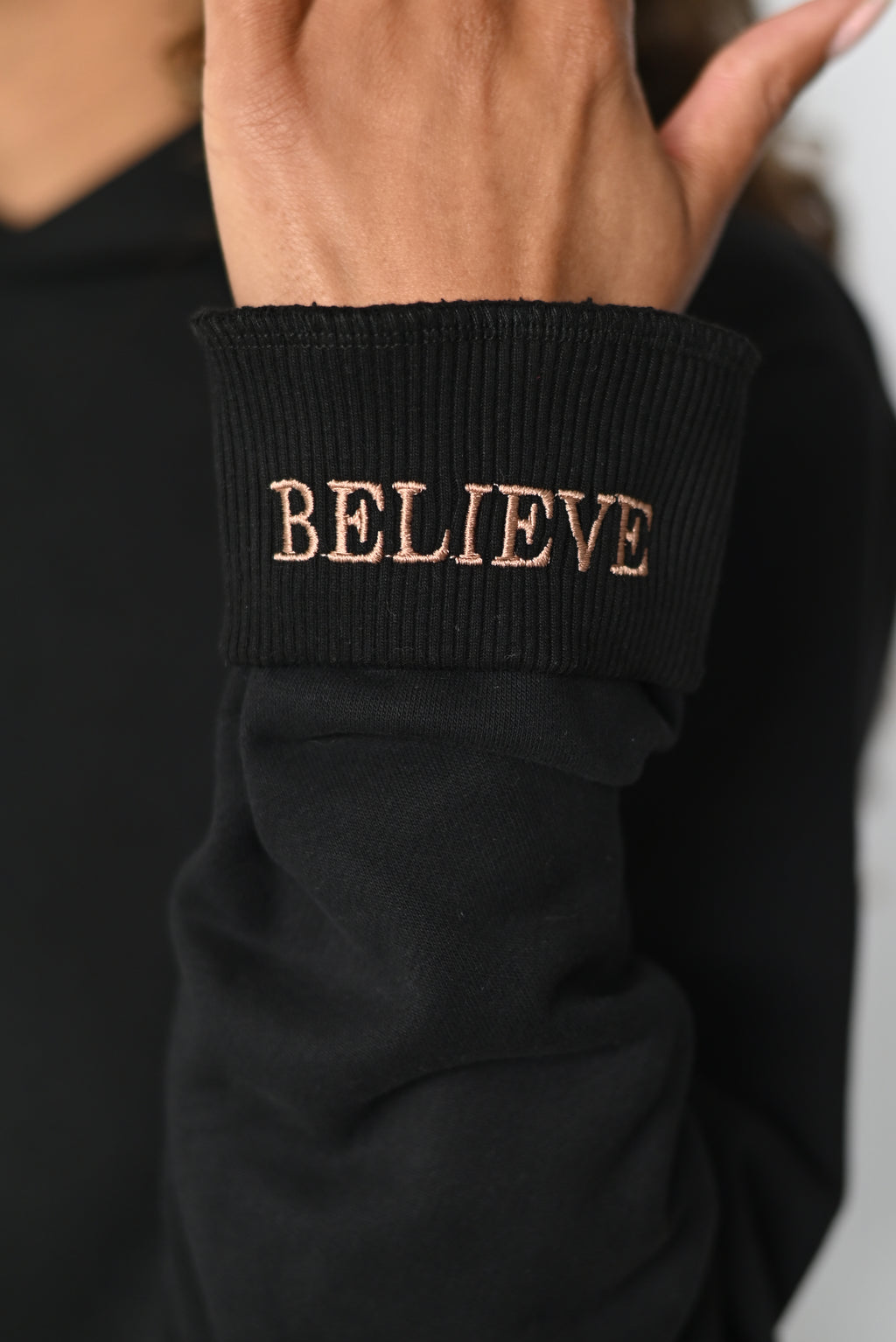 Close-up of the folded cuff of the Believe hoodie with the hidden BELIEVE embroidery