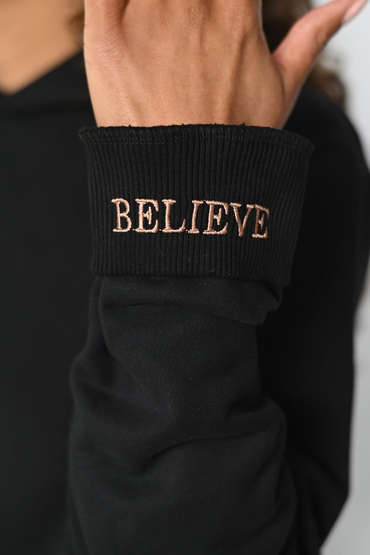 Close-up of the folded cuff of the Believe hoodie with the hidden BELIEVE embroidery